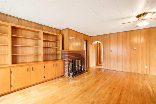 108 Gay St, Salisbury, PA 15558 - unfurnished living room with arched walkways, light wood-style flooring, a ceiling fan, wooden walls, and a brick fireplace