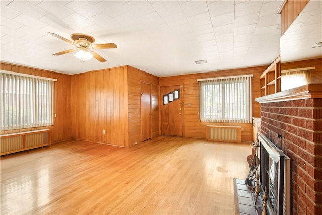 108 Gay St, Salisbury, PA 15558 - unfurnished living room featuring radiator heating unit, a ceiling fan, a fireplace, wood finished floors, and wood walls