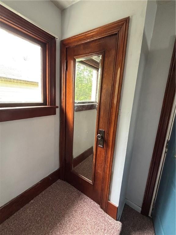 doorway to outside featuring baseboards and carpet floors
