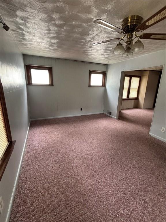 spare room featuring healthy amount of natural light, carpet, and baseboards