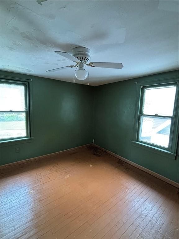 spare room with hardwood / wood-style floors, ceiling fan, and baseboards