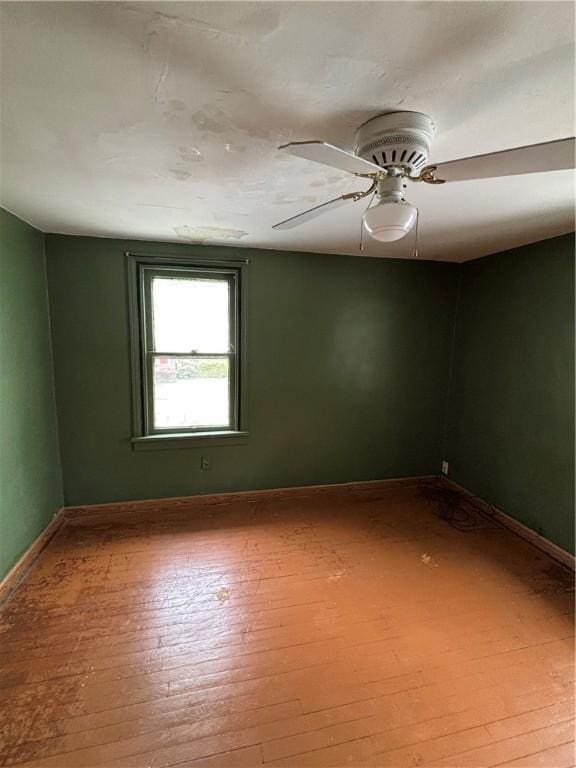 empty room with hardwood / wood-style floors, baseboards, and a ceiling fan