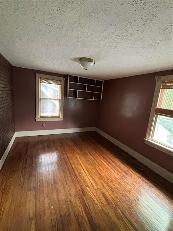 spare room featuring dark wood-style floors, baseboards, and a textured ceiling