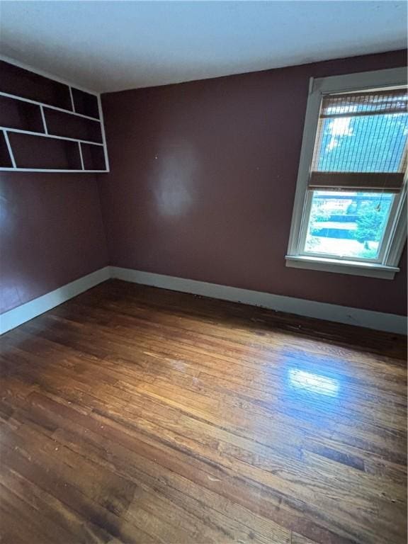 spare room featuring dark wood-type flooring and baseboards