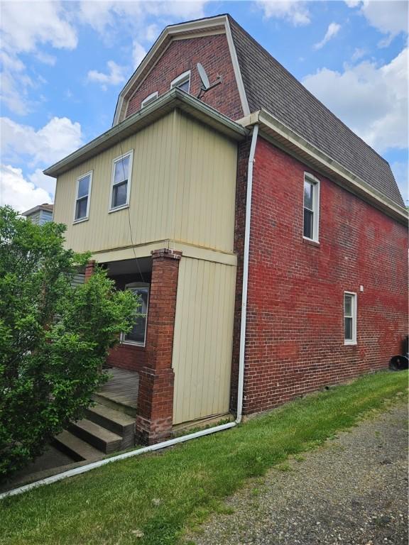 view of side of property with brick siding and roof with shingles