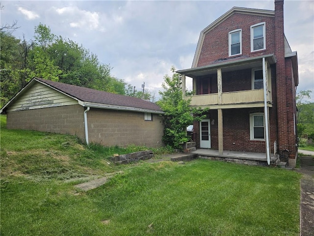 back of property featuring a balcony, a porch, a lawn, brick siding, and a chimney