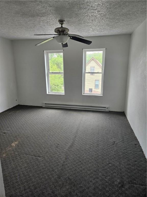 unfurnished room with a baseboard heating unit, carpet, a textured ceiling, and a ceiling fan