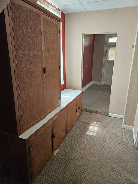 corridor with light colored carpet, baseboards, and a drop ceiling