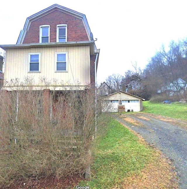 view of front facade with a gambrel roof, gravel driveway, and an outdoor structure