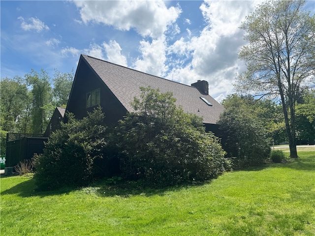 view of property exterior with roof with shingles, a yard, and a chimney