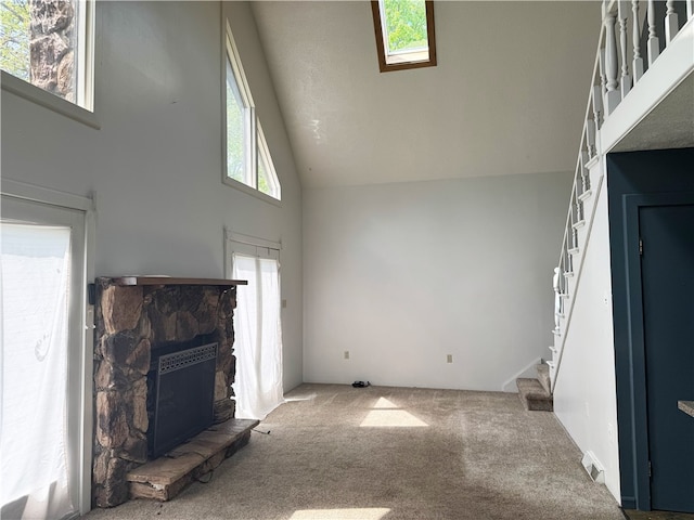unfurnished living room with high vaulted ceiling, carpet floors, a fireplace, and stairway