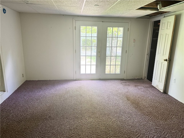 empty room with carpet, a paneled ceiling, and french doors