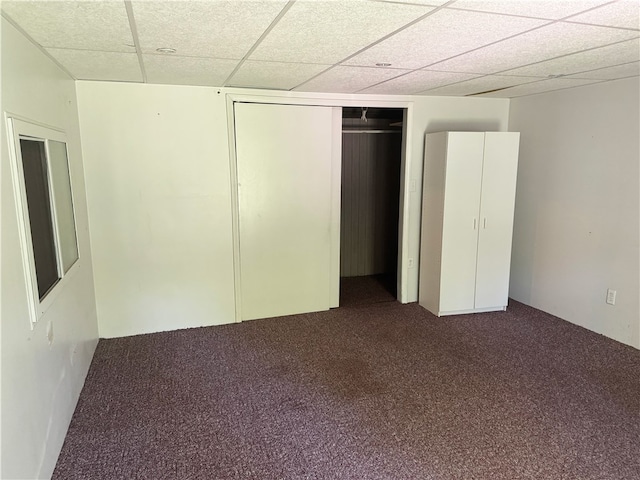 unfurnished bedroom with carpet flooring, a drop ceiling, and a closet