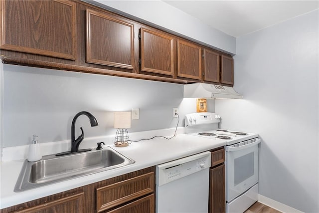 kitchen featuring white appliances, under cabinet range hood, a sink, and light countertops