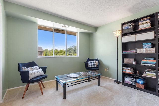 living area featuring carpet flooring, baseboards, and a textured ceiling
