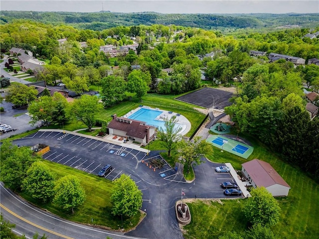 drone / aerial view of a heavily wooded area and a pool area