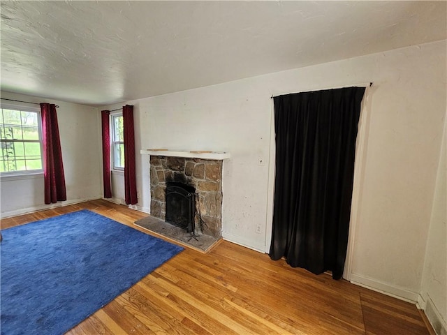 256 Duff Rd, Penn Hills, PA 15235 - unfurnished living room with wood finished floors, a stone fireplace, and baseboards
