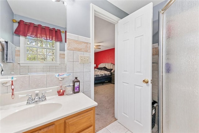 ensuite bathroom featuring vanity, tile patterned flooring, and a shower with door