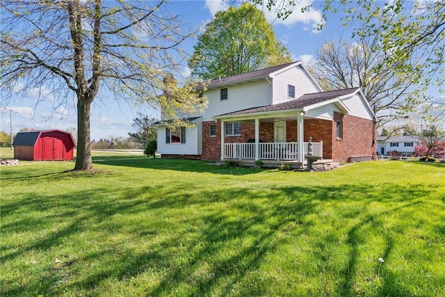 rear view of property featuring covered porch, a storage shed, brick siding, and a lawn