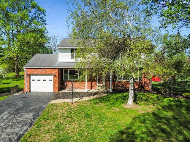 view of front of property featuring brick siding, an attached garage, driveway, and a front yard