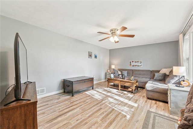 living area featuring a ceiling fan, light wood-type flooring, and baseboards