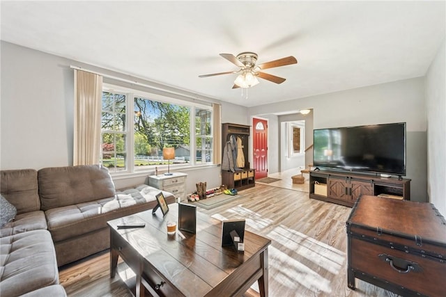 living area with ceiling fan, light wood-style floors, and baseboards
