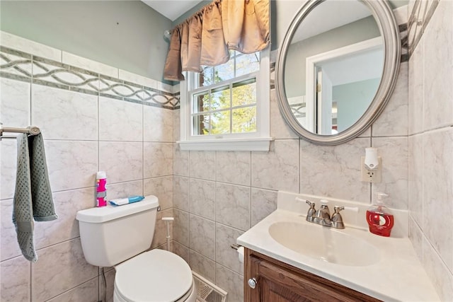 half bathroom featuring tile walls, toilet, and vanity