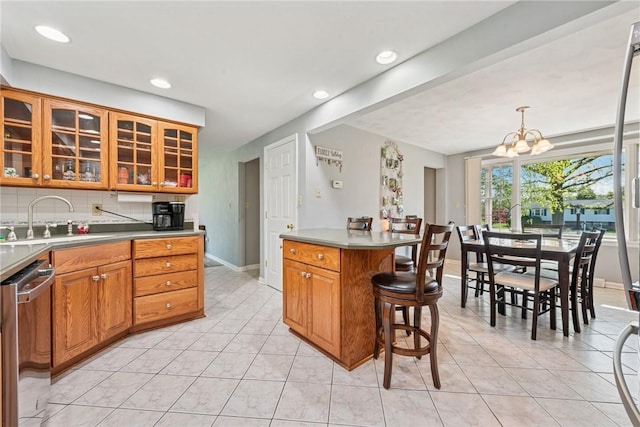 kitchen with a sink, a breakfast bar area, baseboards, stainless steel dishwasher, and light tile patterned flooring