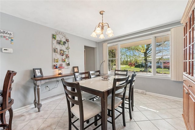 dining area featuring light tile patterned flooring, a chandelier, and baseboards