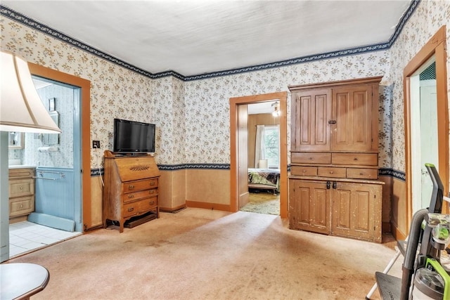 living area featuring wallpapered walls, light colored carpet, and wainscoting