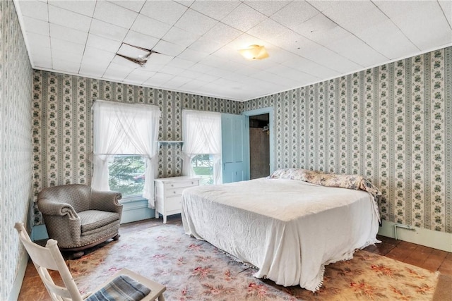 bedroom with wallpapered walls and wood finished floors