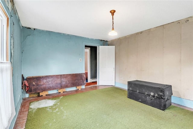 carpeted empty room with a baseboard heating unit