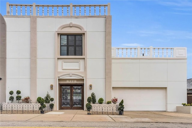 view of front of home featuring french doors, stucco siding, driveway, and an attached garage