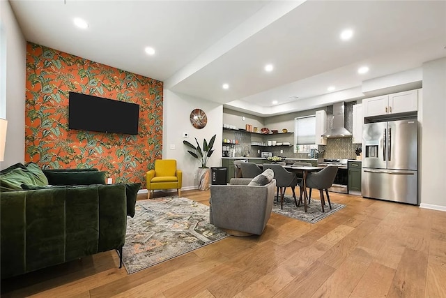 living room with light wood-type flooring, wallpapered walls, recessed lighting, an accent wall, and baseboards
