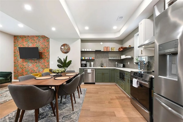 kitchen featuring stainless steel appliances, green cabinetry, open shelves, light wood finished floors, and light countertops