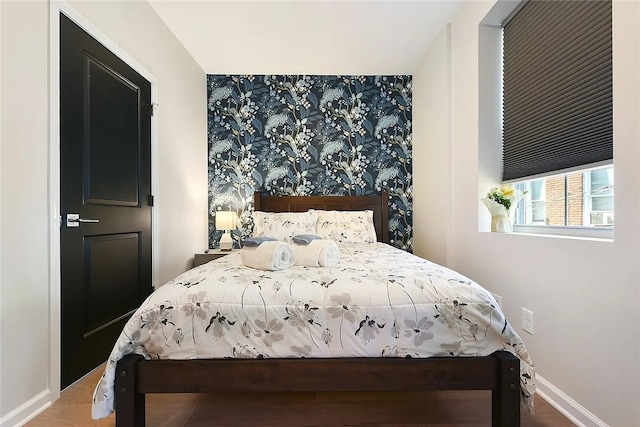 bedroom with wallpapered walls, baseboards, and an accent wall