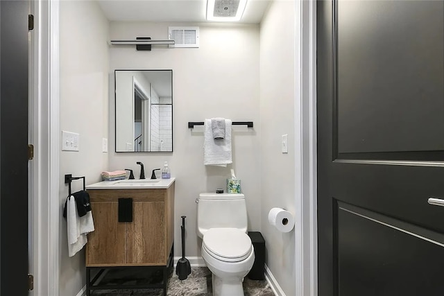 half bathroom with toilet, vanity, and baseboards
