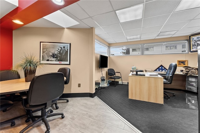 carpeted office space featuring baseboards and a paneled ceiling