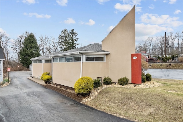 view of side of home featuring stucco siding and a shingled roof