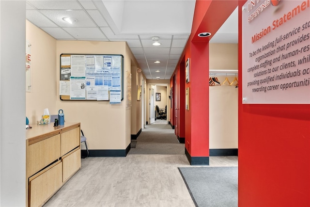 corridor featuring baseboards, a drop ceiling, wood finished floors, and recessed lighting