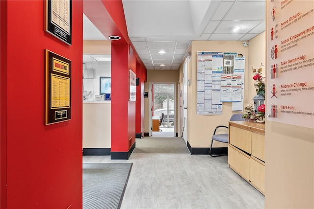 corridor featuring a drop ceiling, baseboards, recessed lighting, and wood finished floors