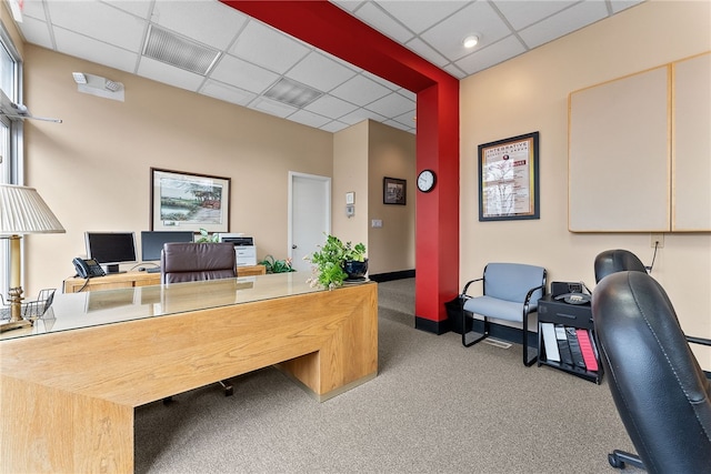 carpeted office space featuring a drop ceiling and baseboards