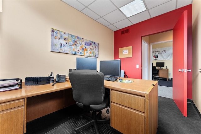 office area with a paneled ceiling and dark carpet