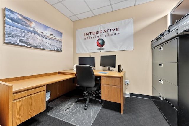 home office with a paneled ceiling and dark colored carpet