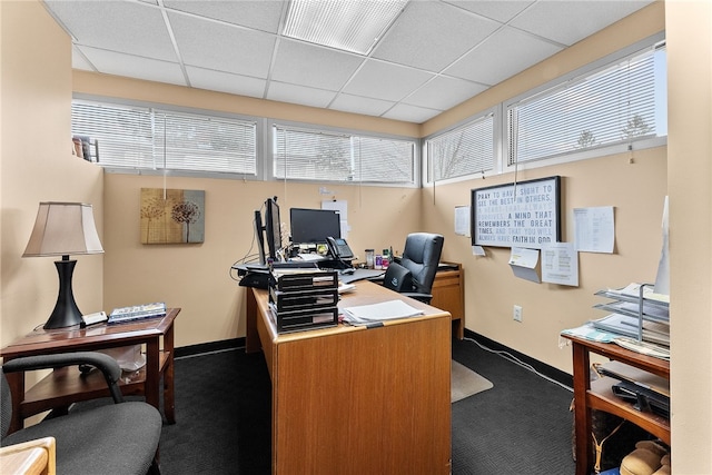 office space with dark carpet, baseboards, and a paneled ceiling