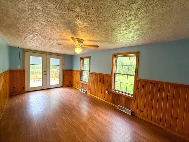155 Elm St, Saint Clair Twp, PA 15954 - unfurnished room featuring a wainscoted wall, wood finished floors, ceiling fan, a textured ceiling, and french doors