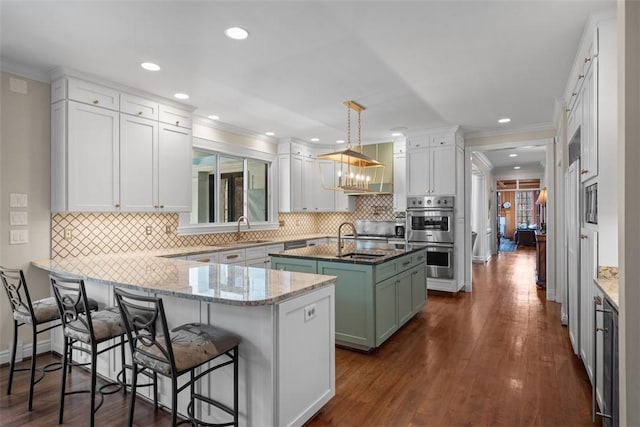 904 Champlain Pl, Adams Twp, PA 15044 - kitchen featuring a sink, a peninsula, double oven, an island with sink, and crown molding