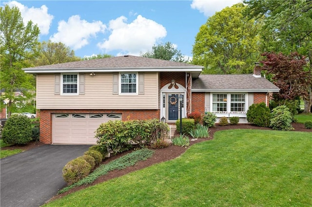 split level home with brick siding, driveway, an attached garage, a front lawn, and a chimney