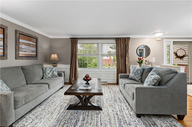 living area featuring wood finished floors, crown molding, and a wainscoted wall
