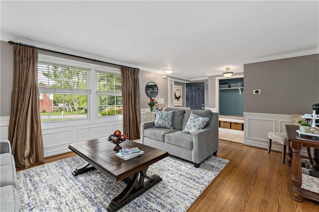 living area with crown molding, a decorative wall, wood finished floors, and a wainscoted wall